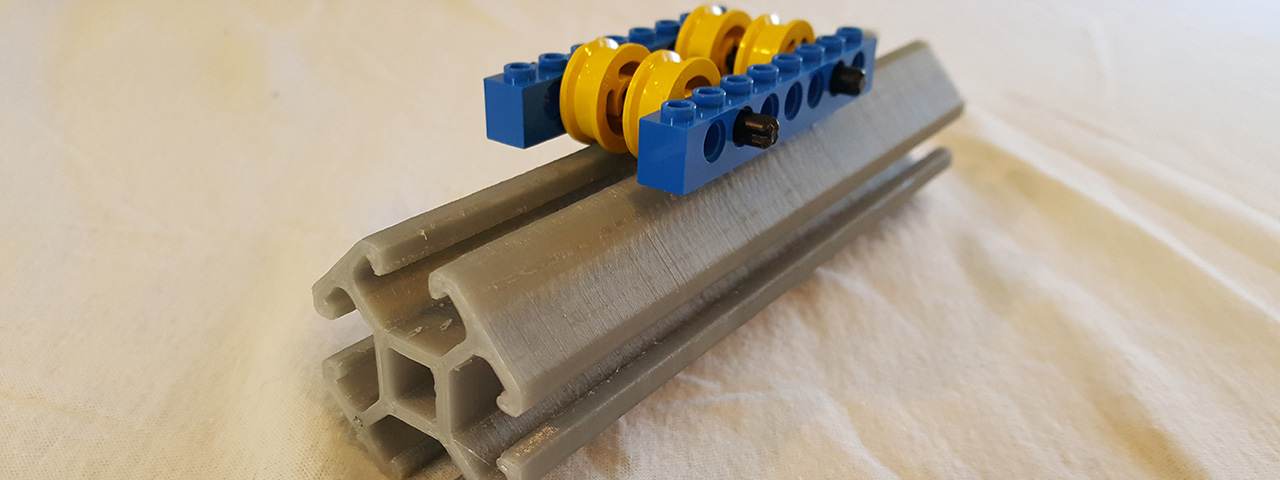 A gray MakeWiths extrusion carrying blue building-brick beams and yellow gears